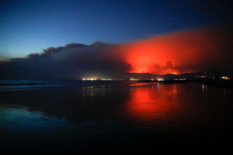A wildfire continues to burn as its red glow is reflected on the beach in Ventura, California. Jae C Hong / AP Photo