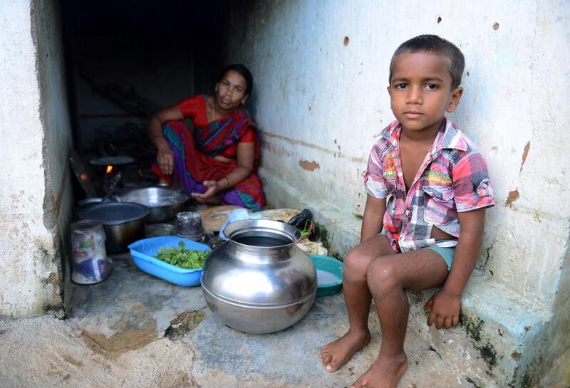 Tribal child K. Jagan (R), who lost his father in a road accident, sits with his mother K. Mangi at their home. Noah Seelam / AFP