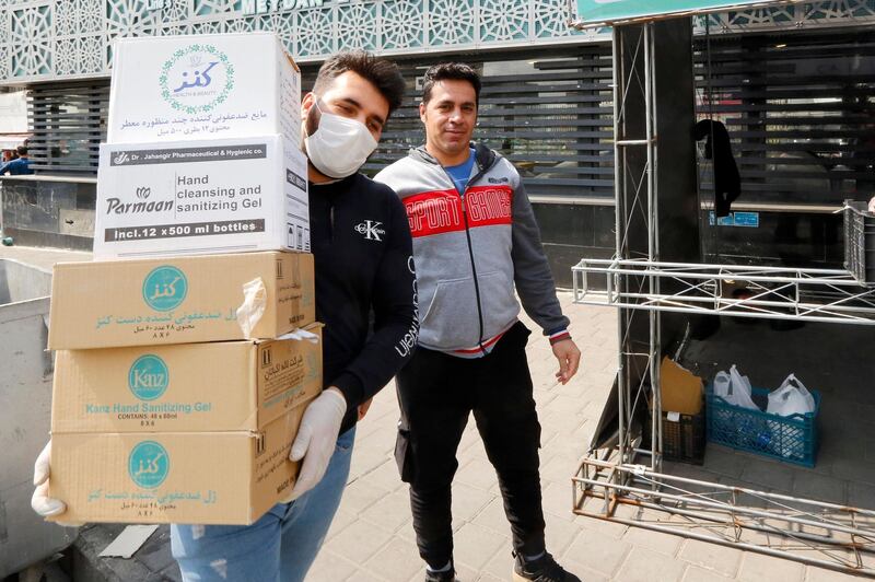 A man wearing a protective mask carries boxes containing disinfectants, March 15. AFP