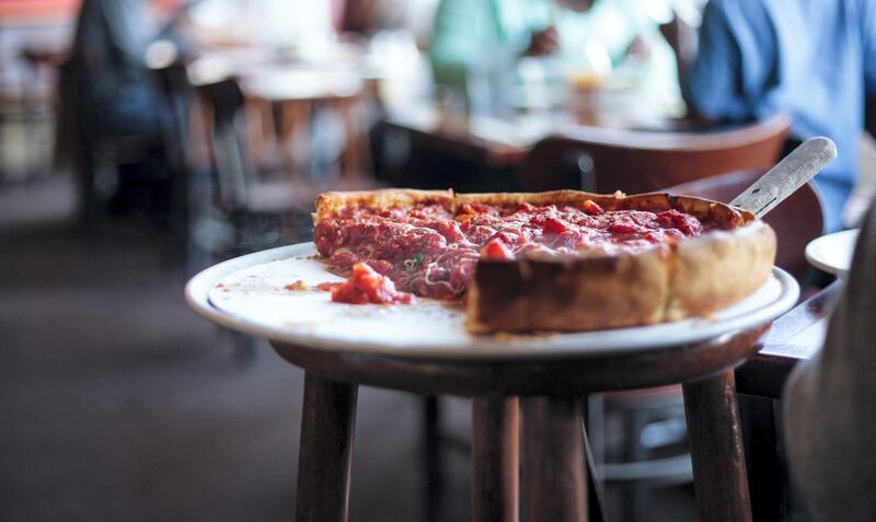 A partial deep dish pizza on a raised tray, with a serving spatula, in a restaurant.