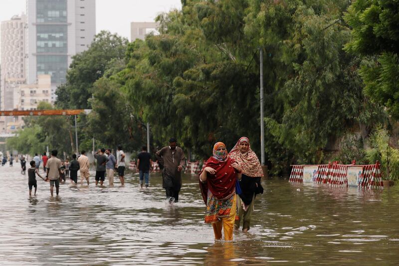 People wade through a flooded road after the monsoon rain, as the outbreak of Covid-19 continues, in Karachi, Pakistan. Reuters