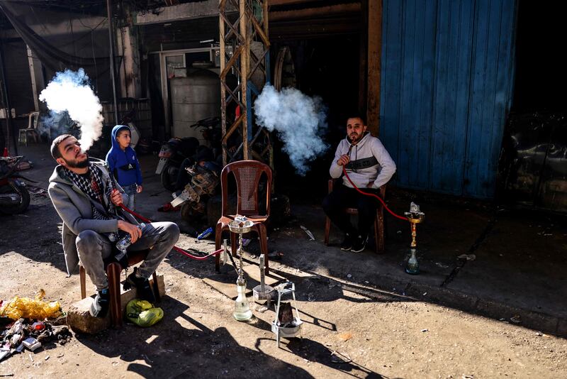 Lebanese men smoke water pipes as they take a break outside their workshop in an alley of Tripoli's impoverished neighbourhood of Bab al-Tabbaneh.