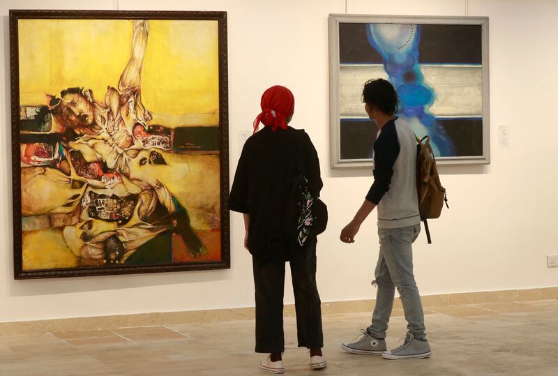 Visitors look at paintings by Iraqi artists Suad Al-Attar, left, and Rafa Al Nasiri.