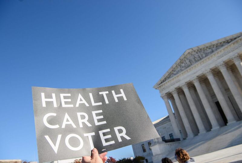 A demonstrator holds a sign in front of the US Supreme Court in Washington as the high court opened arguments in the long-running case over Affordable Care Act.   AFP