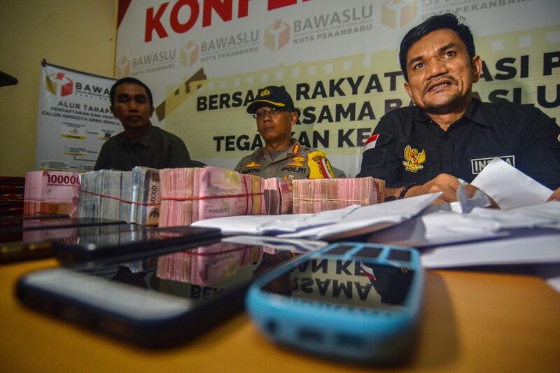 Indra Khalid Nasution (R), head of the Elections Supervisory Agency (Bawaslu) and police display seized money, believed to be distributed to influence voters ahead of the upcoming general elections.