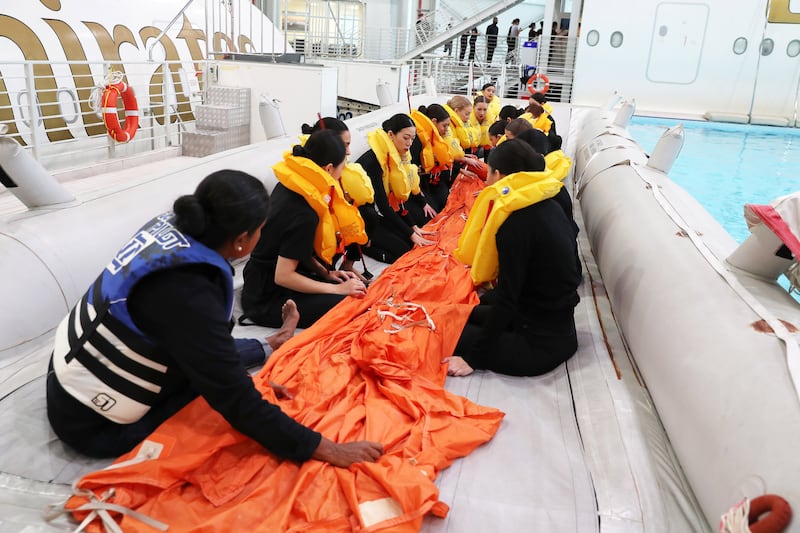 Trainees are shown how to unravel and attach the protective orange cover for the life raft.
