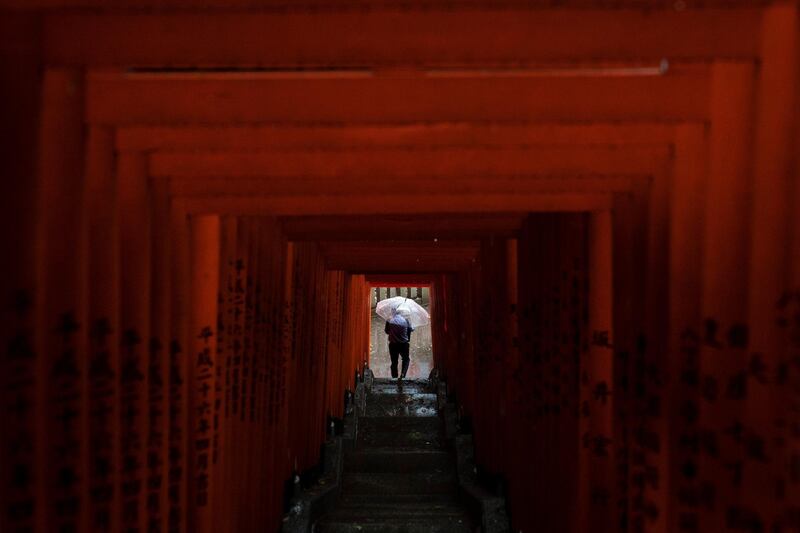 A man with an umbrella walks through a tunnel of torii gates at the Hie Shrine Monday in Tokyo. AP Photo