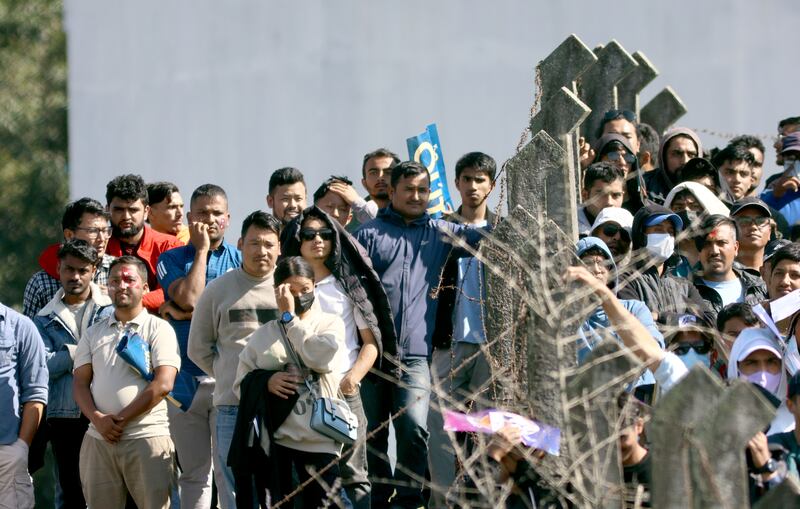 Spectators stand near the boundary wall of the Mulpani Cricket Ground in Kathmandu