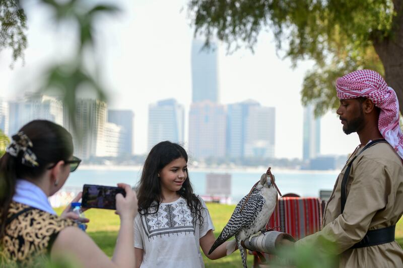 A young girl poses with a falcon at the Heritage Village during the 51st National Day long weekend in Abu Dhabi. Khushnum Bhandari / The National