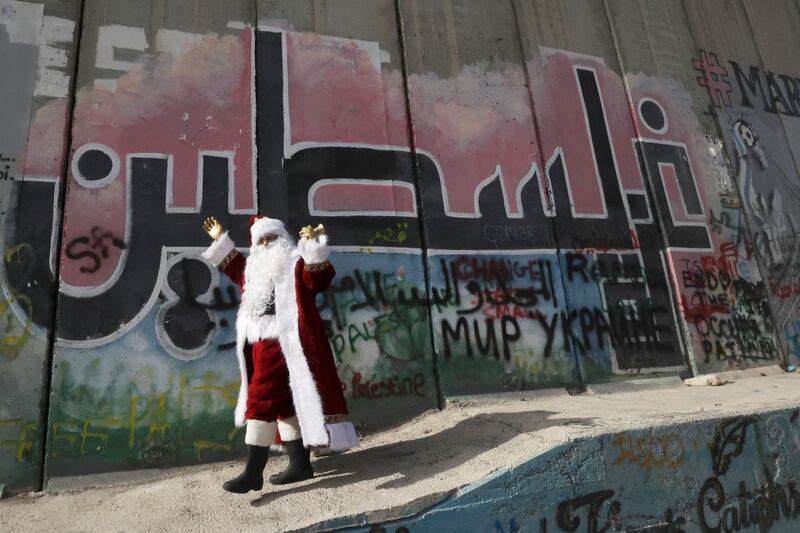 A 'Santa Claus' next to graffiti reading 'Palestine' in Arabic on Israel's separation wall in the Palestinian city of Bethlehem. AFP