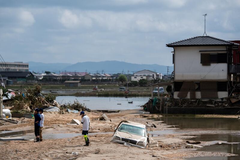 People inspect their damaged homes in a flood hit area in Mabi, Okayama. AFP