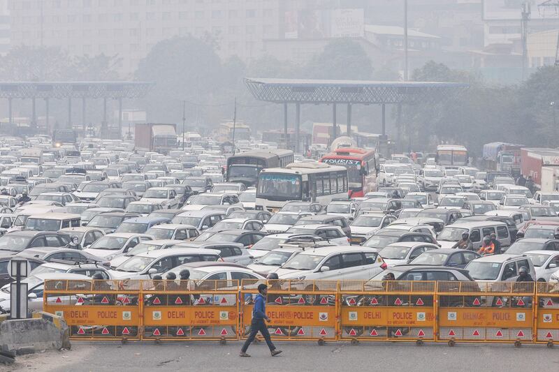 A man walks past barricades in front of vehicles stuck in heavy traffic at the New Delhi-Gurgaon Sirhaul motorway. AFP