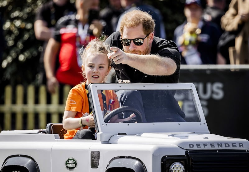 Harry is driven by a child in a children's car. EPA