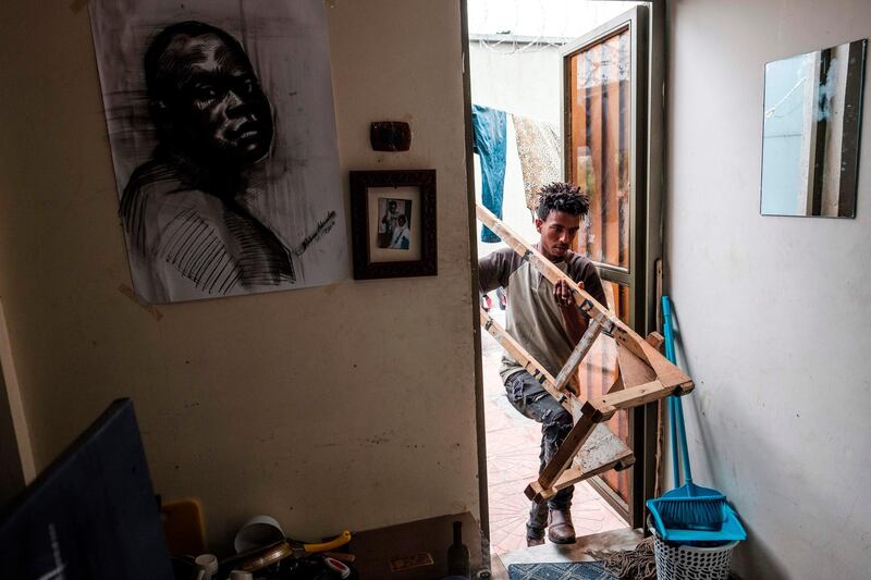 Eritrean artist Nebay Abraha, 23, enters his room and studio carrying an easel. AFP