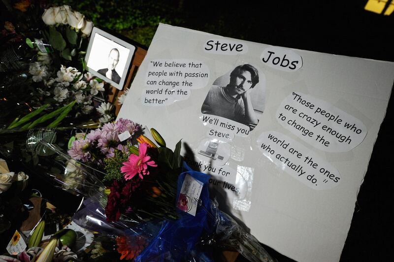 CUPERTINO, CA - OCTOBER 05: Flowers and an iPad showing a picture of Steve Jobs are placed at a makeshift memorial for Steve Jobs at the Apple headquarters on October 5, 2011 in Cupertino, California. Jobs, 56, passed away after a long battle with pancreatic cancer. Jobs co-founded Apple in 1976 and is credited, along with Steve Wozniak, with marketing the world's first personal computer in addition to the popular iPod, iPhone and iPad.   Kevork Djansezian/Getty Images/AFP== FOR NEWSPAPERS, INTERNET, TELCOS & TELEVISION USE ONLY ==
 *** Local Caption ***  989267-01-09.jpg