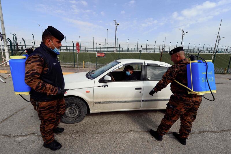 Member of the security forces, carrying disinfecting material, urge a driver along a deserted street to return home, in the central Iraqi city of Najaf. AFP