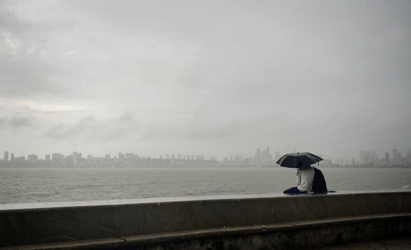 An Indian couple sits at the seafront during showers in Mumbai. Punit Paranjpe / AFP Photo