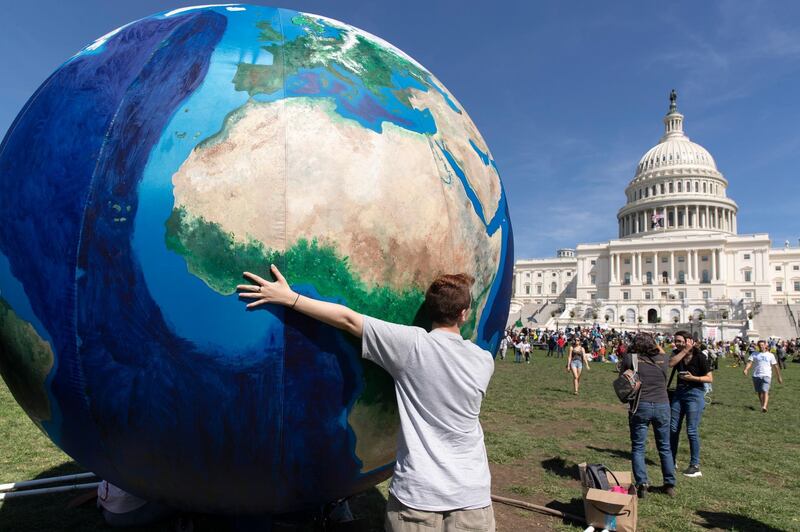 A youth touches an inflatable globe at the West Front of the US Capitol as crowds dispersed following the DC Climate Strike March in Washington, DC, USA. EPA