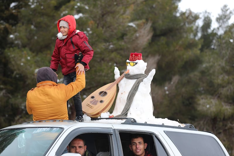 A snowman dressed in traditional Libyan garb is taken for a ride.