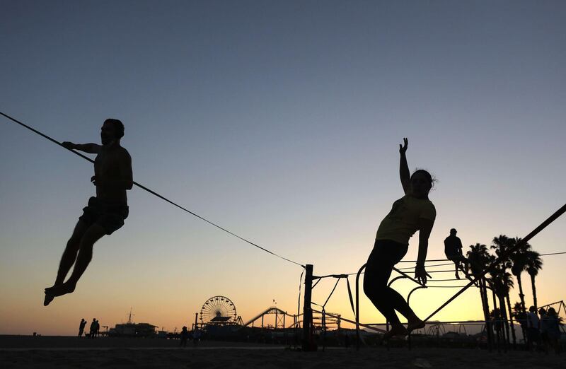 People slackline on the Santa Monica beach in Los Angeles County, California where beaches and piers will be closed during the Fourth of July weekend to slow the spread of the coronavirus.   AFP