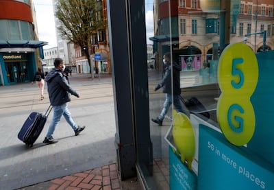 A pedestrian, wearing a protective mask, walks past an advertisement for 5G network services at an EE store, operated by BT Group Plc, in Birmingham, U.K., on Monday, April 6, 2020. Telecom masts that enable the next generation of wireless communication were set on fire in the U.K. in recent days, apparently by people motivated by a theory that the tech helps spread the coronavirus. Photographer: Darren Staples/Bloomberg