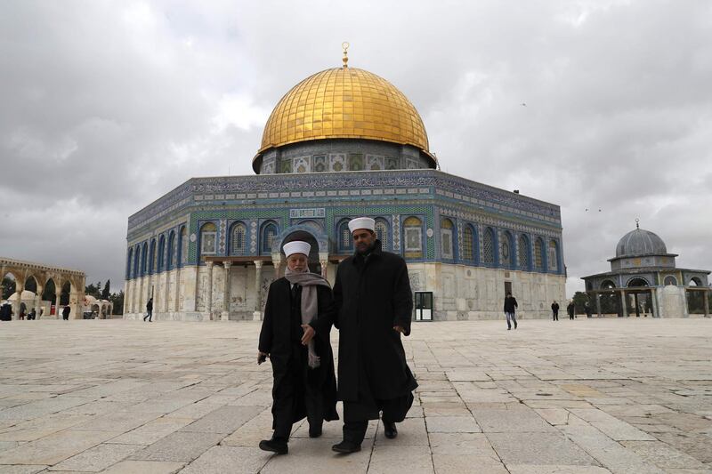 Palestinians walk outside the Dome of the Rock in Jerusalem's Old City in al-Aqsa mosque compound on January 23, 2018. / AFP PHOTO / AHMAD GHARABLI