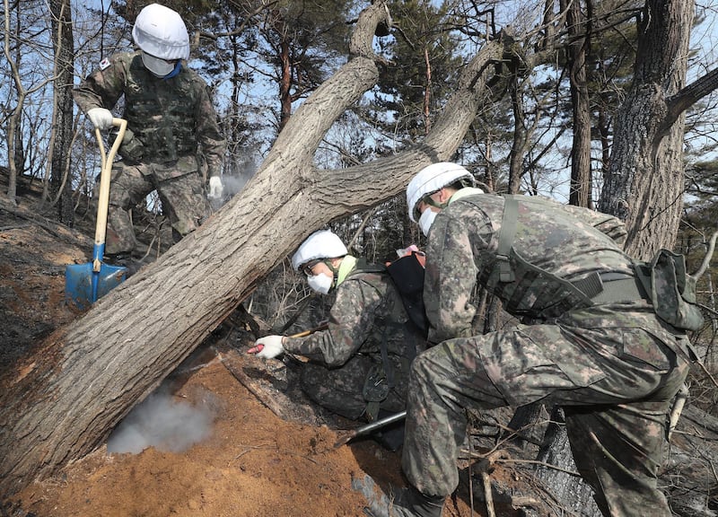 Soldiers try to put out embers from a fire on a mountain. Yonhap / EPA