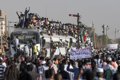 TOPSHOT - Sudanese protesters from the city of Atbara, sitting atop a train, cheer upon arriving at the Bahari station in Khartoum on April 23, 2019. The passengers, who had travelled from the town of Atbara where the first protest against ousted president Omar al-Bashir erupted on December 19, chanted "freedom, peace, justice". Many protesters perched on the roof of the train, waving Sudanese flags as it chugged through north Khartoum's Bahari railway station before winding its way to the protest site, an AFP photographer said. / AFP / OZAN KOSE
