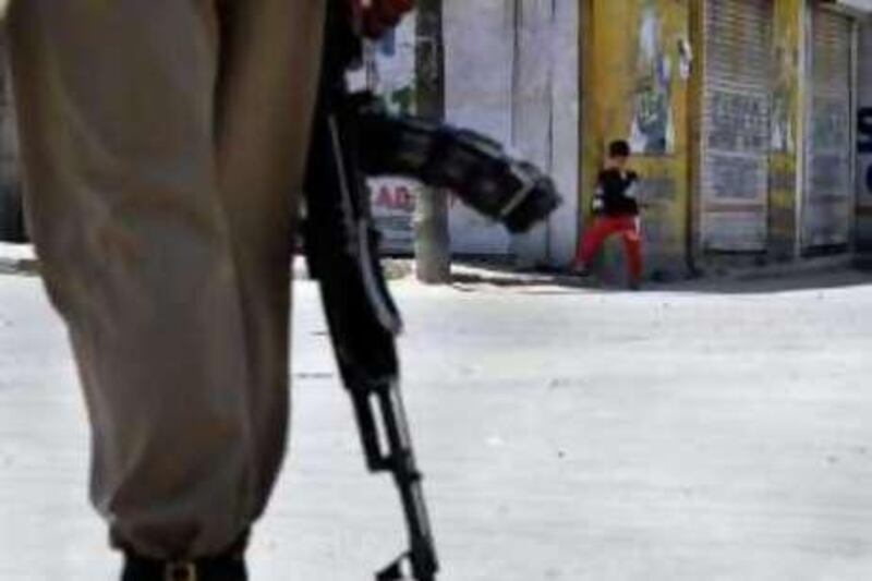 A Kashmiri boy looks on from a distance as an Indian paramilitary soldier patrols on a deserted street in Srinagar, India, Sunday, June 13, 2010. Indian authorities imposed restrictions on the movement of private vehicles in Indian-administered Kashmir's main city Sunday anticipating protests after a teenage boy was killed, Friday allegedly by a rubber bullet fired by police. (AP Photo/Mukhtar Khan) *** Local Caption ***  DEL112_India_Kashmir_.jpg