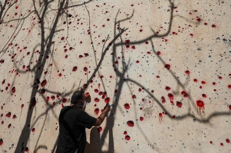 An Iranian Kurdish Peshmerga member of the Iranian Kurdistan Democratic Party (KDPI) sprays red paint at holes in a wall made by shrapnel from a rocket attack days earlier at the party's headquarters in Koysinjaq, 100 kilometres east of the capital of the northern Iraqi Kurdish autonomous region Arbi. - At least a dozen members of the Iranian Kurdish rebel group were killed on September 8 in the a rocket attack on their headquarters carried out by Iran's Revolutionary Guards. The Kurdistan Democratic Party of Iran (KDPI) has carried out sporadic attacks inside Iran from its rear-bases in Iraq and is blacklisted as a "terrorist" group by Tehran.  AFP