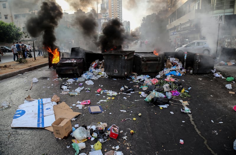 Protesters block Beirut roads with bins and burning tyres.