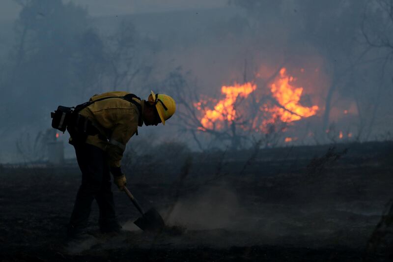 A firefighter works to put out hot spots on a fast moving wildfire. Mike Blake / Reuters
