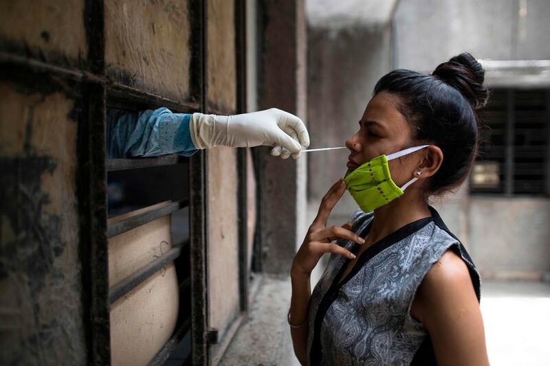 A health official collects a swab sample from a woman in New Delhi, India. AFP