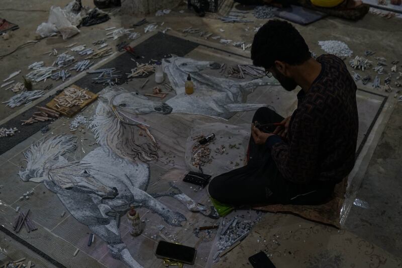 A worker prepares a large mosaic panel that he has been working on for several days.