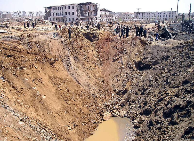 Rescuers pass by a large crater caused by a catastrophic explosion at the railway station in Ryongchon, North Korea, 24 April 2004.   Foreign aid workers reaching the site of the North Korean train explosion on Saturday reported a scene of utter devastation and confirmed about half of the 154 victims were children.                                  AFP PHOTO/WFP (Photo by WFP / WFP / AFP)