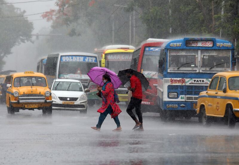 Commuters with umbrellas cross a road during heavy rain caused by Asani in Kolkata. Reuters