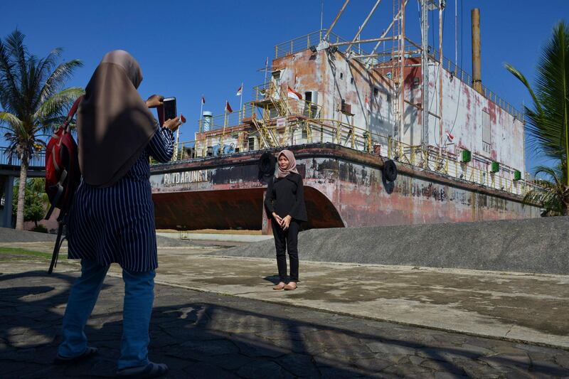 Visitors posing by the tsunami memorial in Banda Aceh.  AFP