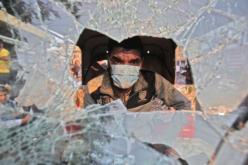 A tuktuk (motorised rickshaw) driver sits behind his broken windshield in his vehicle during clashes between anti-government protesters and security forces in the Iraqi capital Baghdad's Rasheed street near al-Ahrar bridge. AFP