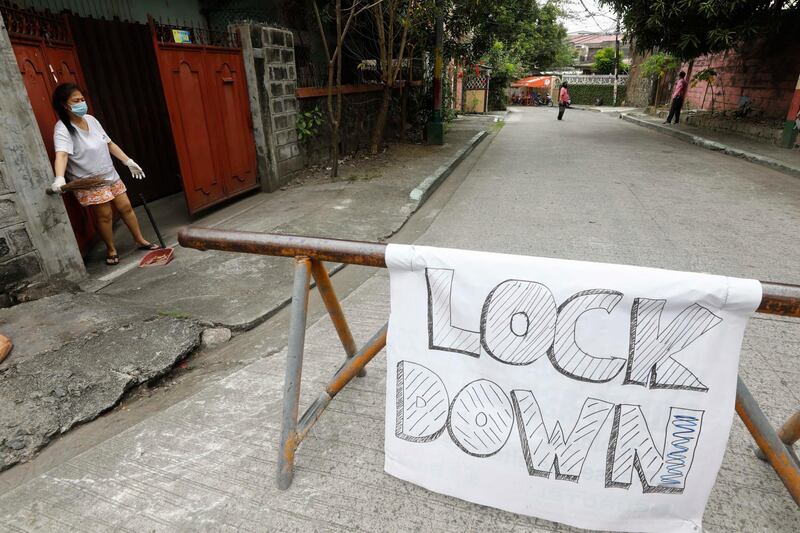 A resident cleans in front of her home on a street under lockdown following a spike in COVID-19 positive cases in Manila. EPA