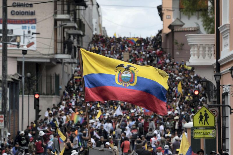 QUITO, ECUADOR - OCTOBER 09: A demonstrator waves an Ecuadorian flag near the Presidential Palace of Carondelet during protests against the end of subsidies to gasoline and diesel announced by President Lenin Moreno's government on October 9, 2019 in Quito, Ecuador. Truckers and taxi drivers began to block highways near the country which threatens access to the capital city of Quito, located in a mountain valley at 2,800 meters above sea level.  Students, workers and indigenous residents also joined the protests. The national government has decided to move the capital to the coastal city of Guayaquil. Moreno accuses supporters of his predecessor, Rafael Correa, of trying to overthrow his government. Correa denies any involvement and calls for elections now rather than at the end of Morenos term on 2021. (Photo by Jorge Ivan Castaneira Jaramillo/Getty Images)