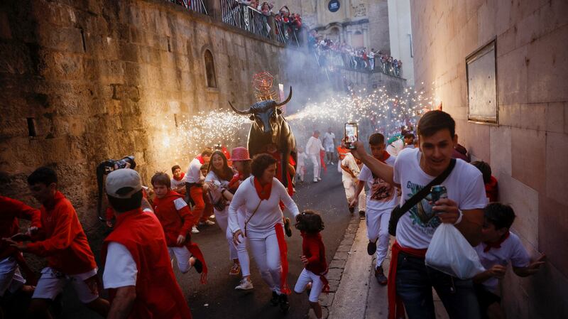 Revellers run next to the Fire Bull, a man carrying a bull figure packed with fireworks, during the San Fermin festival in Pamplona, Spain. Reuters