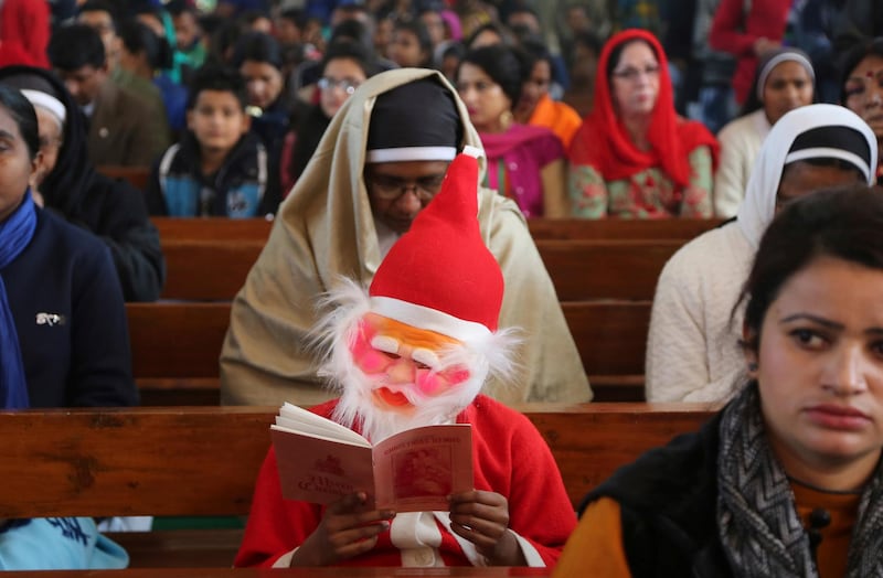 An Indian boy wearing a Santa Claus costume is seated with other worshippers at Saint Mary's Garrison Church on Christmas Day in Jammu, India. Channi Anand / AP Photo.