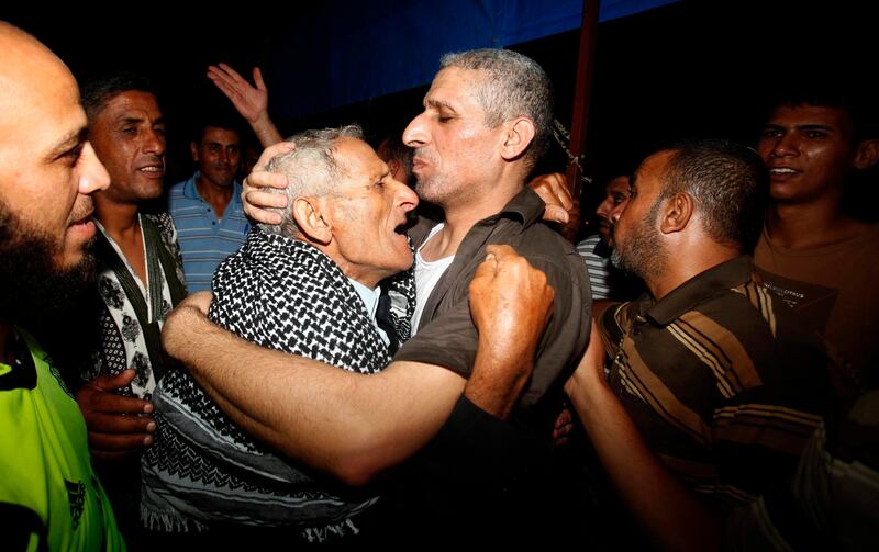 Freed Palestinian prisoner Ateya Abu Moussa (3rd R), who was held by Israel for 20 years, hugs his father upon arriving at his family's house in Khan Younis in the southern Gaza Strip August 14, 2013. Israel freed 26 Palestinian prisoners on Wednesday to keep U.S.-sponsored peacemaking on course for a second round of talks, but diplomacy remained dogged by Israeli plans for more Jewish homes on land the Palestinians claim for a future state. Moussa was convicted in the killing of Israeli Issac Rotenberg in 1994. REUTERS/Ibraheem Abu Mustafa (GAZA - Tags: POLITICS TPX IMAGES OF THE DAY) *** Local Caption ***  GAZ33_PALESTINIANS-_0814_11.JPG