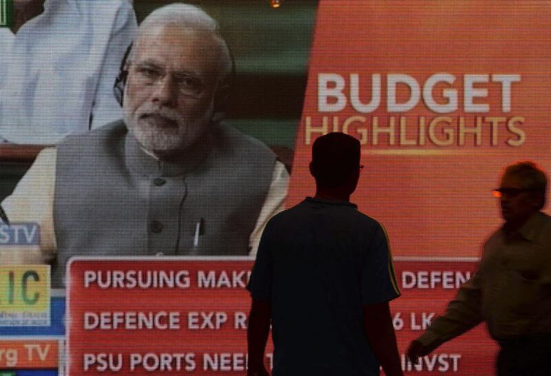 Indian office-workers walk past a digital screen showing prime minister Narendra Modi listening to finance minister Arun Jaitley deliver his Budget speech. (Punit Paranjpe/ AFP)