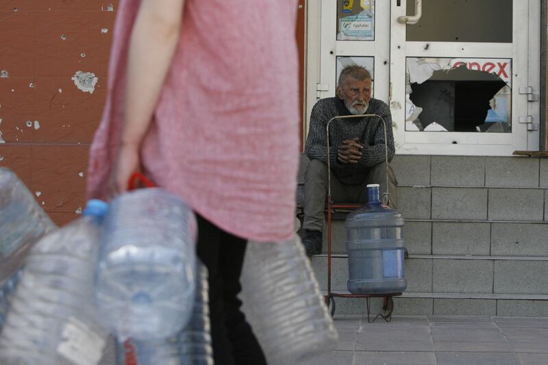 A man waits to collect water in Mariupol. AFP