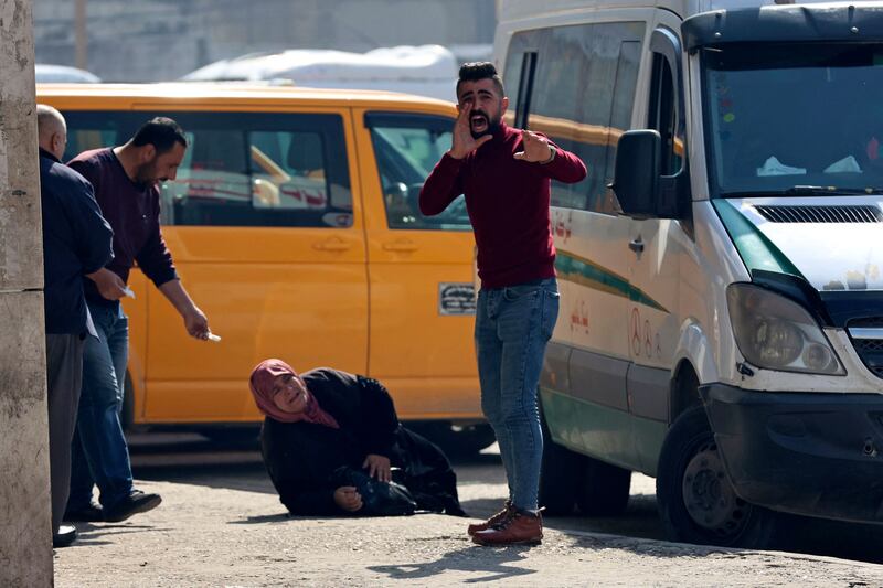 Bystanders help a Palestinian woman wounded in the raid. AFP