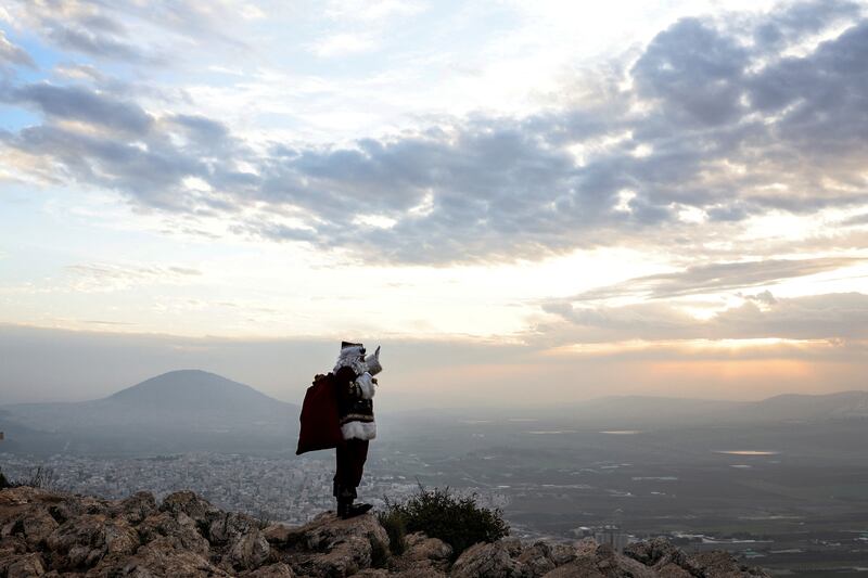 Issa Kassissieh, dressed as Santa Claus, waves and poses for members of the media as he stands on Mount Precipice in front of Mount Tabor close to Nazareth in northern Israel. Reuters