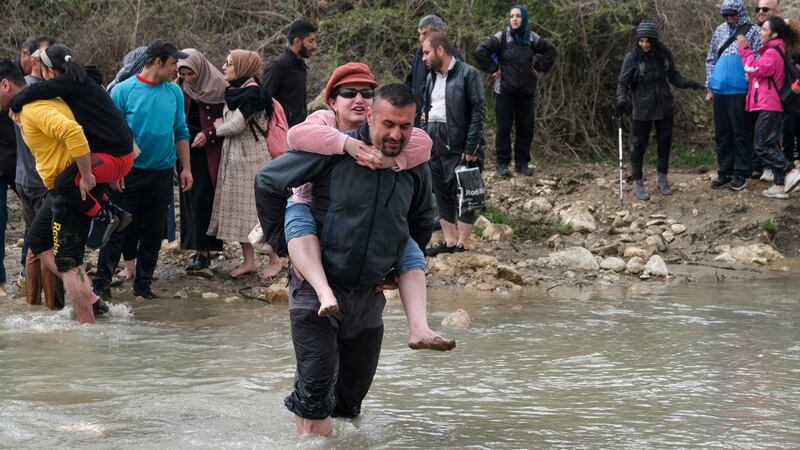 A mountaineer carries a blind girl across a river. 