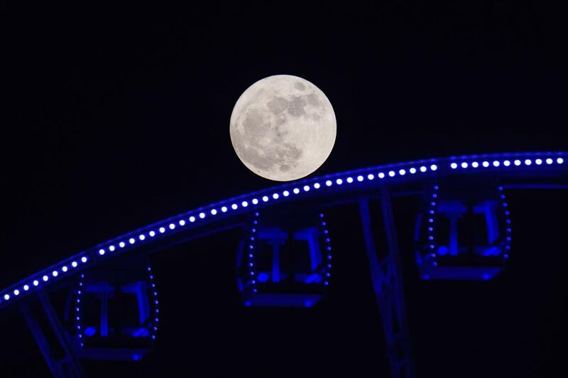The supermoon rises behind a Ferris wheel in Hong Kong. Anthony Wallace / AFP Photo