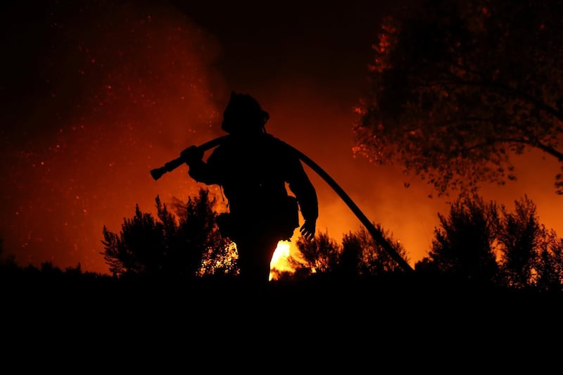 A firefighter works at the top of a hill as the Lilac Fire, a fast moving wild fire, burns through Bonsall, California, U.S., December 7, 2017.      REUTERS/Mike Blake